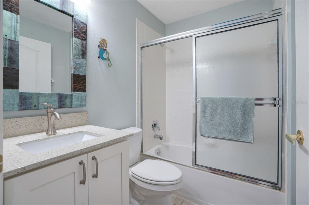 A bathroom features a white vanity, a toilet, and a shower-tub combination with sliding doors — 5310 HYLAND HILLS AVENUE UNIT 2124, SARASOTA, FL