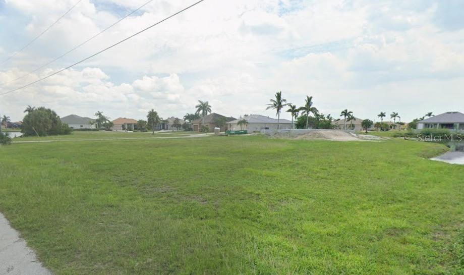 A vacant, grassy residential lot features palm trees and a view of a nearby canal — 17170 BARCREST LANE, PUNTA GORDA, FL