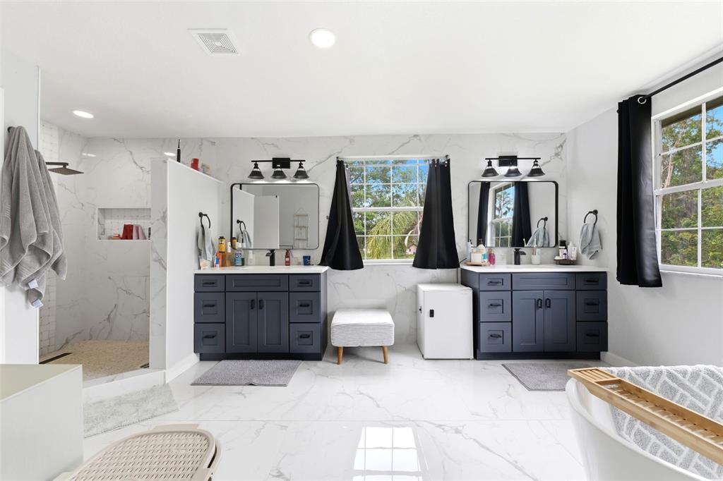 A spacious bathroom features dual dark vanities, a walk-in shower, and a freestanding tub — 19003 CEDAR LANE, LUTZ, FL