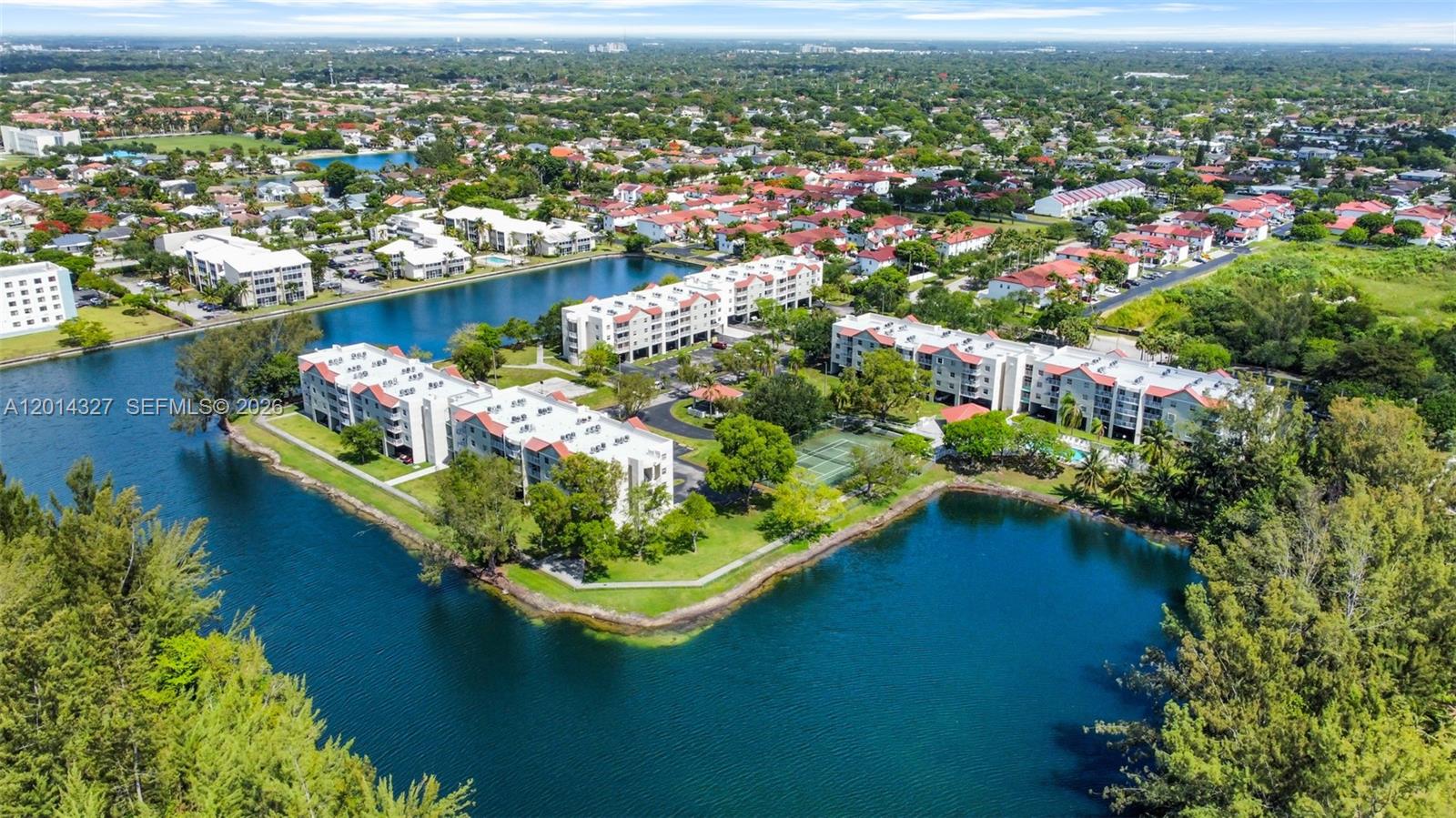 An aerial view shows multi-story apartment buildings situated along a lake with surrounding green space — 8200 SW 210th St # 103, Cutler Bay FL 33189, CUTLER BAY, FL