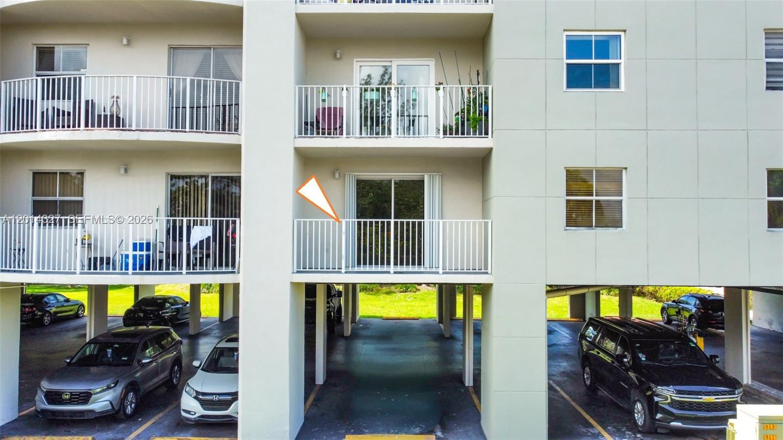 An exterior view shows a multi-story apartment building with balconies and covered ground-level parking — 8200 SW 210th St # 103, Cutler Bay FL 33189, CUTLER BAY, FL