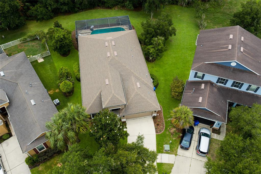 An aerial view shows three suburban houses with roofs, driveways, and a screened-in pool — 17463 NEW CROSS CIRCLE, LITHIA, FL