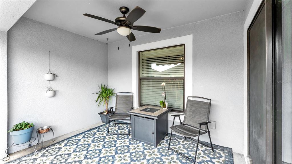 A covered patio features a ceiling fan, a patterned rug, two chairs, and a fire pit — 5739 LACAR WAY, LAKELAND, FL