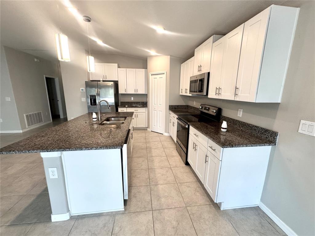 A kitchen features white cabinets, granite countertops, stainless steel appliances, and a large center island — 929 ANCHOR BEND DRIVE, RUSKIN, FL