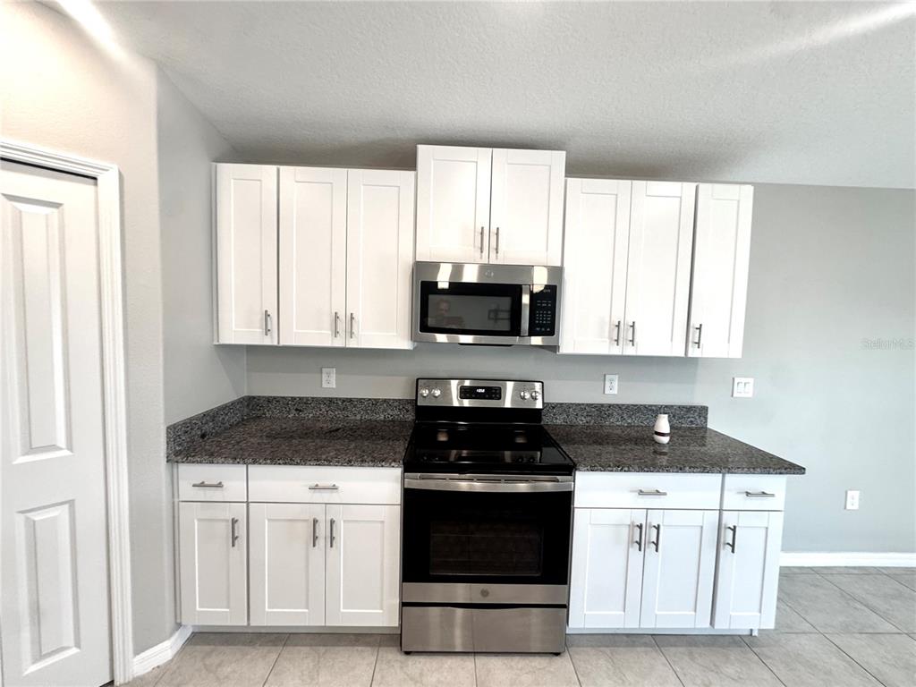 A kitchen features white cabinets, granite countertops, and stainless steel appliances — 929 ANCHOR BEND DRIVE, RUSKIN, FL