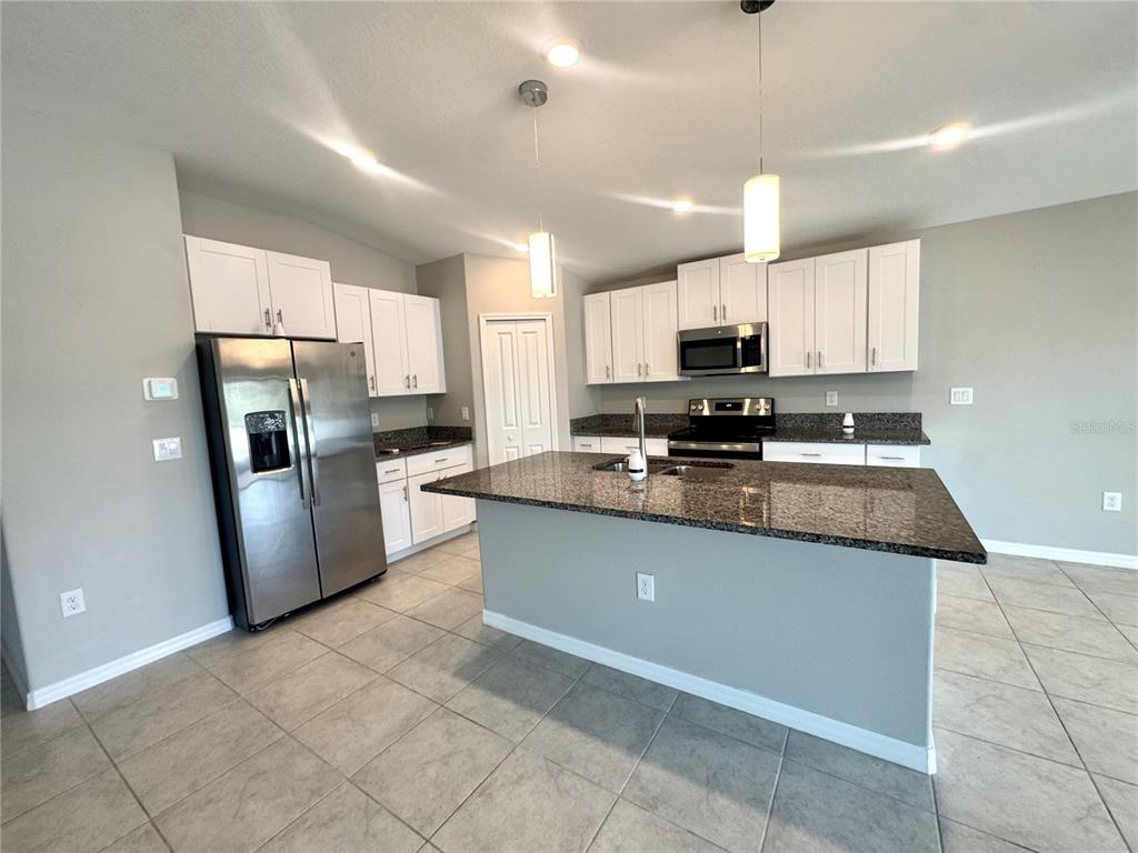 A kitchen features white cabinets, granite countertops, stainless steel appliances, and a central island — 929 ANCHOR BEND DRIVE, RUSKIN, FL