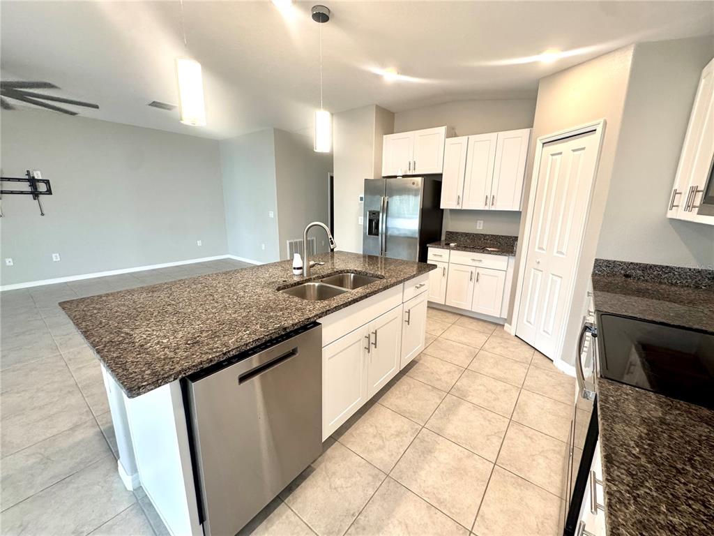 A kitchen features white cabinets, granite countertops, a stainless steel dishwasher, and tile flooring — 929 ANCHOR BEND DRIVE, RUSKIN, FL