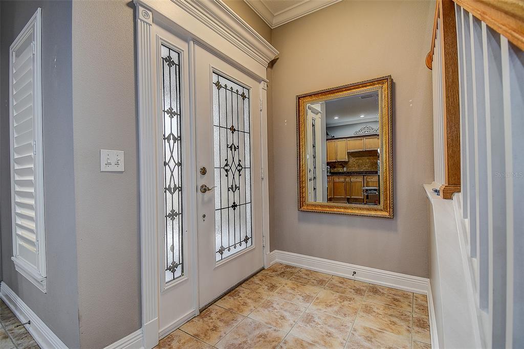 An entryway features a white front door with glass panels, tile flooring, and a wall mirror — 256 VALENCIA CIRCLE, ST PETERSBURG, FL