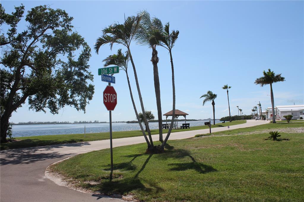 A street corner with a stop sign and street signs overlooking a waterfront park area — 10315 CORTEZ ROAD W UNIT 1/2 BV, BRADENTON, FL