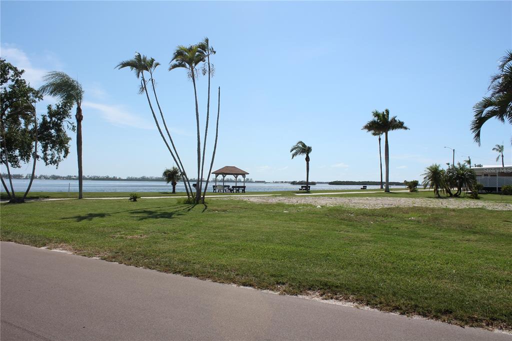 A grassy park area features palm trees, a small gazebo, and a view of water — 10315 CORTEZ ROAD W UNIT 1/2 BV, BRADENTON, FL