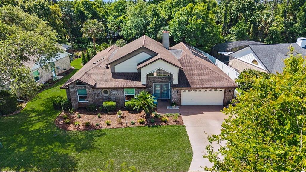 An aerial view of a brick house with a brown shingled roof and attached garage — 47 CARRIAGE CREEK WAY, ORMOND BEACH, FL