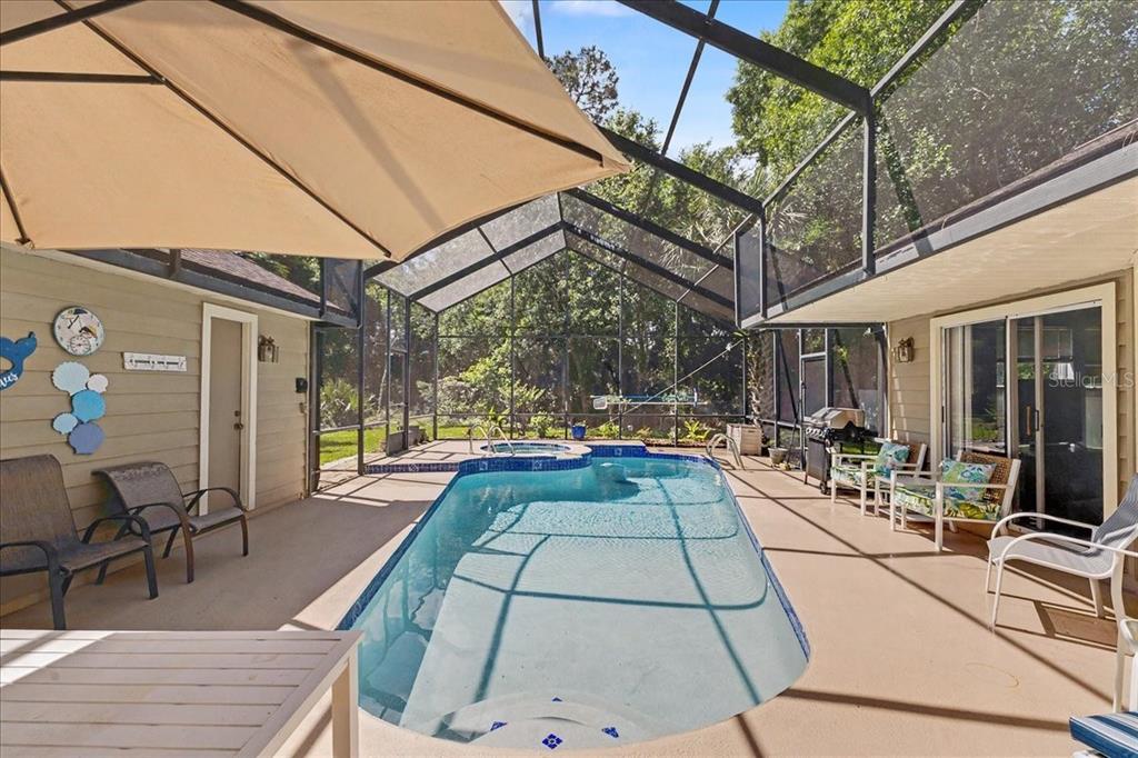 A screened-in patio features a swimming pool, a hot tub, and outdoor seating — 47 CARRIAGE CREEK WAY, ORMOND BEACH, FL