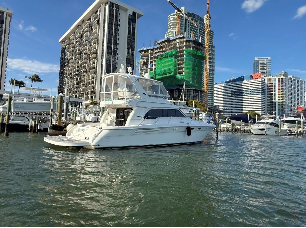 A white motor yacht is docked in a marina surrounded by high-rise buildings — 1901 Brickell Ave Slip 29A, Miami FL 33129, MIAMI, FL
