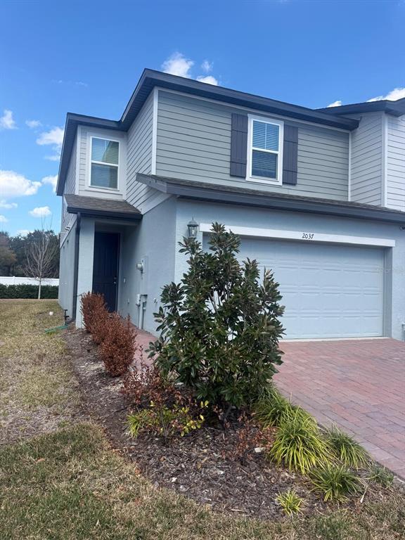 A two-story house with a light blue stucco exterior, gray siding, and a brick driveway — 2037 CRAPE JASMINE LANE, ORLANDO, FL