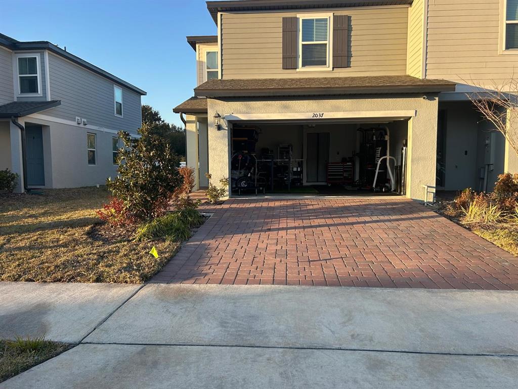 A paved driveway leads to an open garage attached to a two-story residential building — 2037 CRAPE JASMINE LANE, ORLANDO, FL