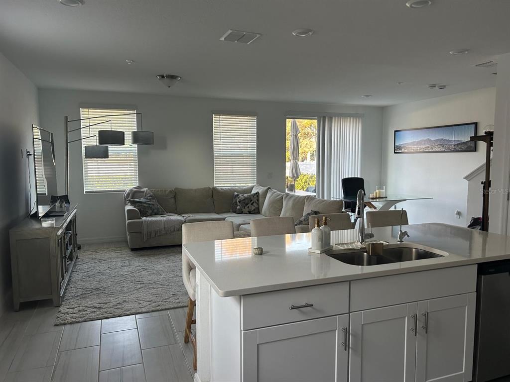 A bright open-concept living room and kitchen featuring a white island and sectional sofa — 2037 CRAPE JASMINE LANE, ORLANDO, FL