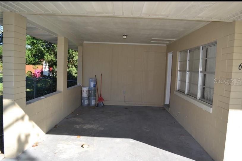 A covered concrete carport features block walls, a ceiling light, and a broom in corner — 609 S MONTGOMERY AVENUE, DELAND, FL