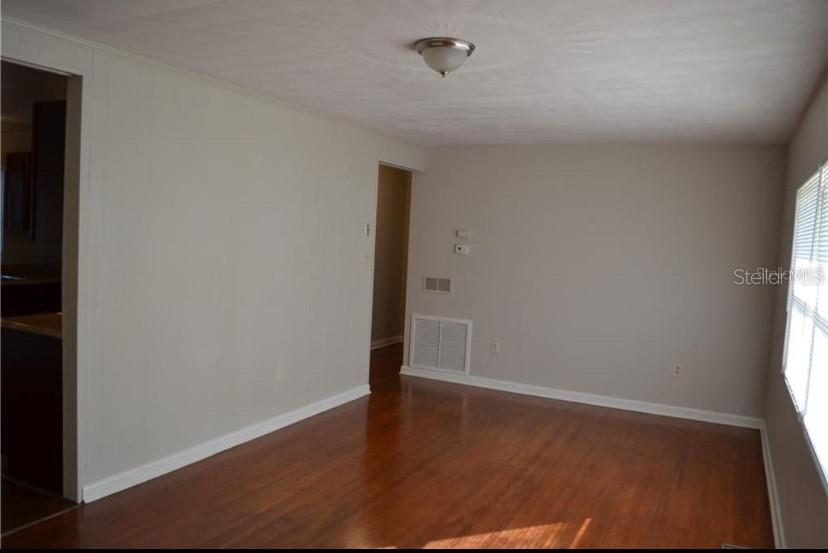 An interior view of a room with light-colored walls, hardwood flooring, and a ceiling light — 609 S MONTGOMERY AVENUE, DELAND, FL