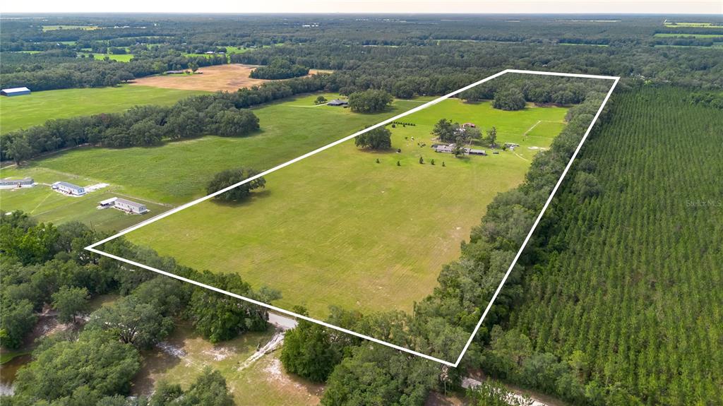 An aerial view shows a large, rectangular plot of land featuring a house and pasture — 11990 156TH STREET, MC ALPIN, FL