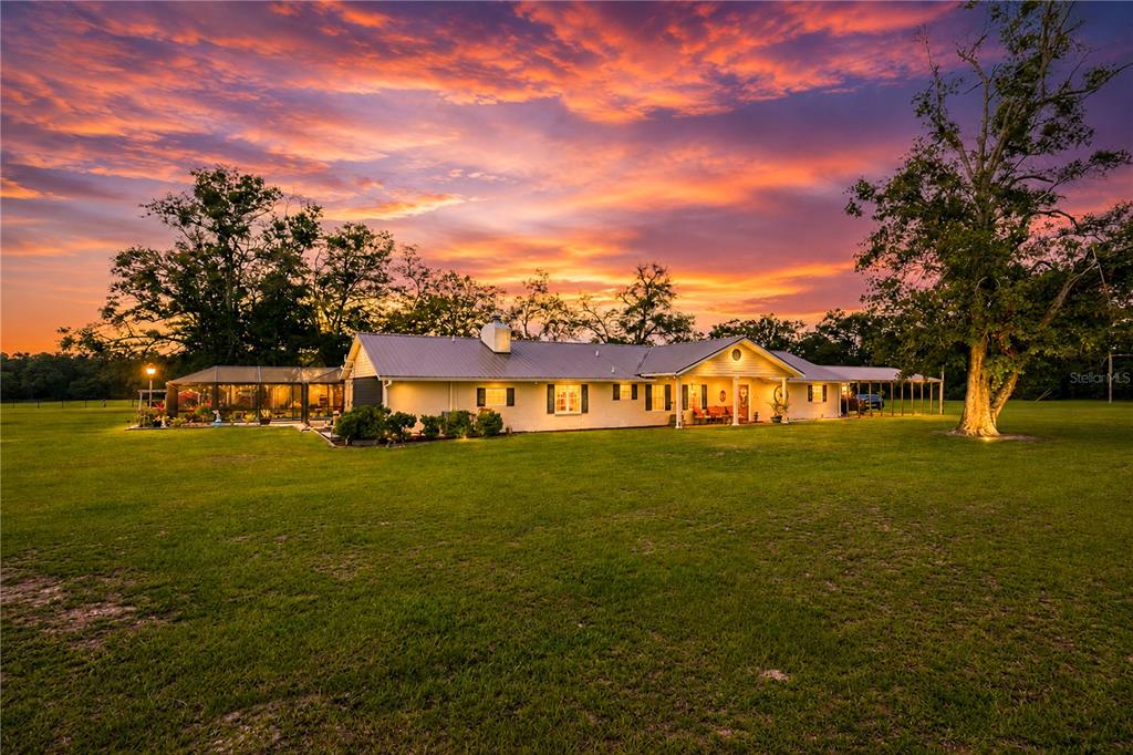 A single-story house with a metal roof and screened patio sits on a grassy lawn — 11990 156TH STREET, MC ALPIN, FL