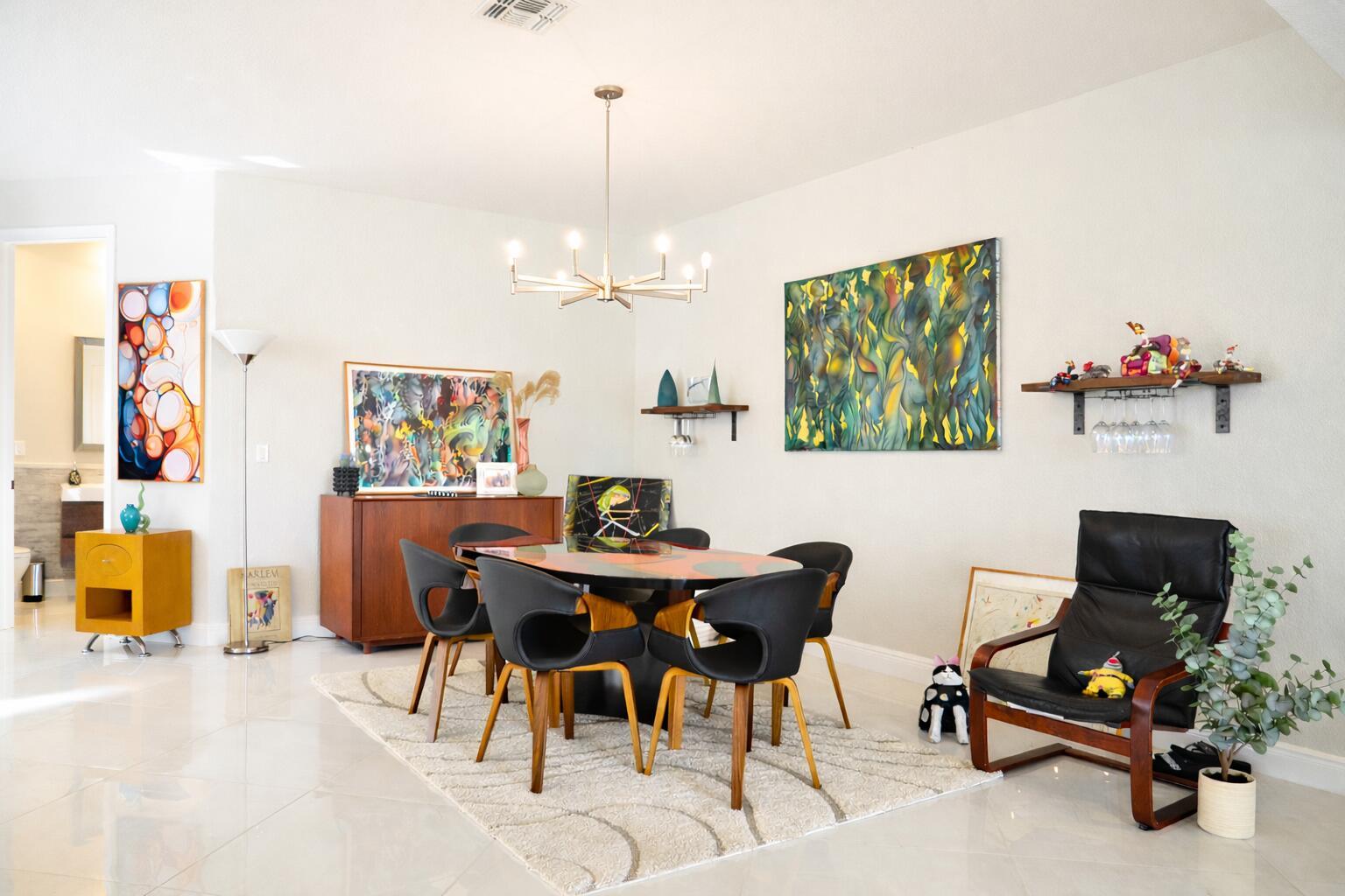 A dining room features a modern chandelier, a glass-topped table, and colorful abstract wall art — 9720 Phipps Lane, Wellington FL 33414, WELLINGTON, FL