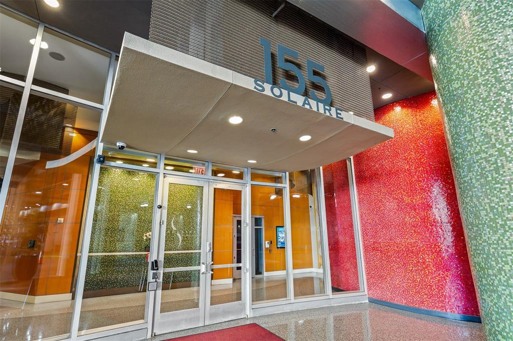 The entrance to a modern building features glass doors under a canopy labeled 155 Solaire — 155 S COURT AVENUE UNIT 2403, ORLANDO, FL