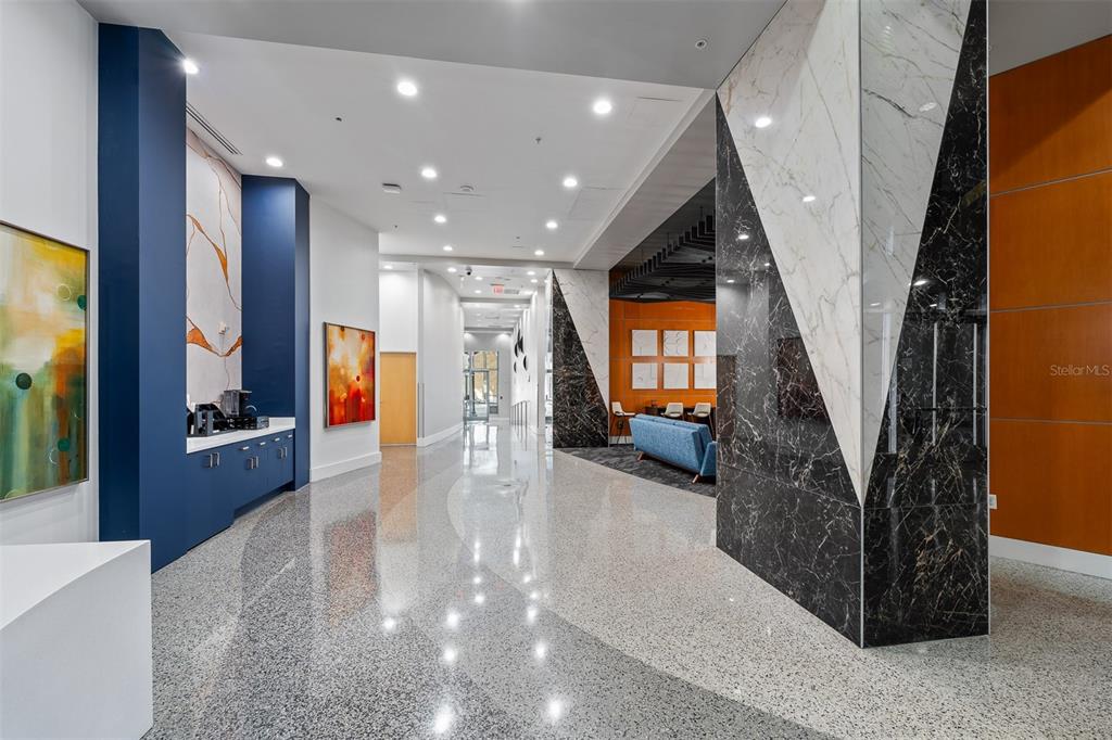 A modern lobby features polished terrazzo floors, geometric marble pillars, and a blue refreshment station — 155 S COURT AVENUE UNIT 2403, ORLANDO, FL