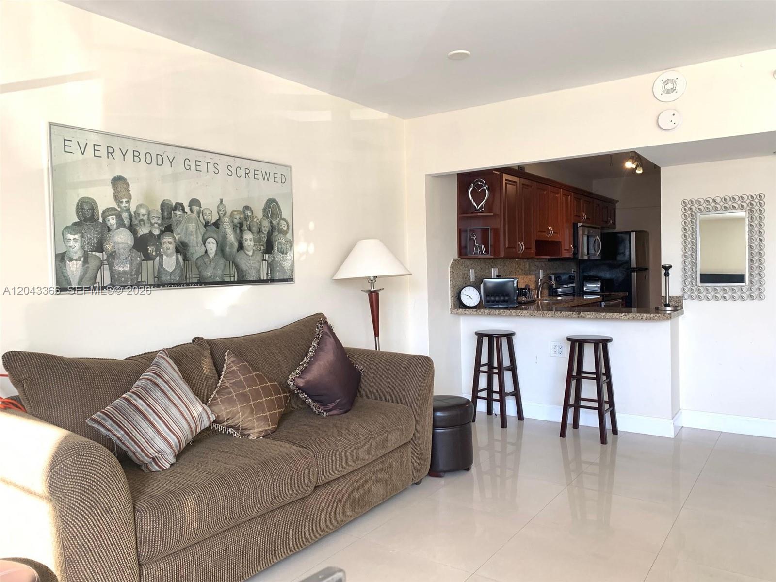 A living room features a brown sofa, a breakfast bar with stools, and wall art — 100 Lincoln Rd # 316, Miami Beach FL 33139, MIAMI BEACH, FL