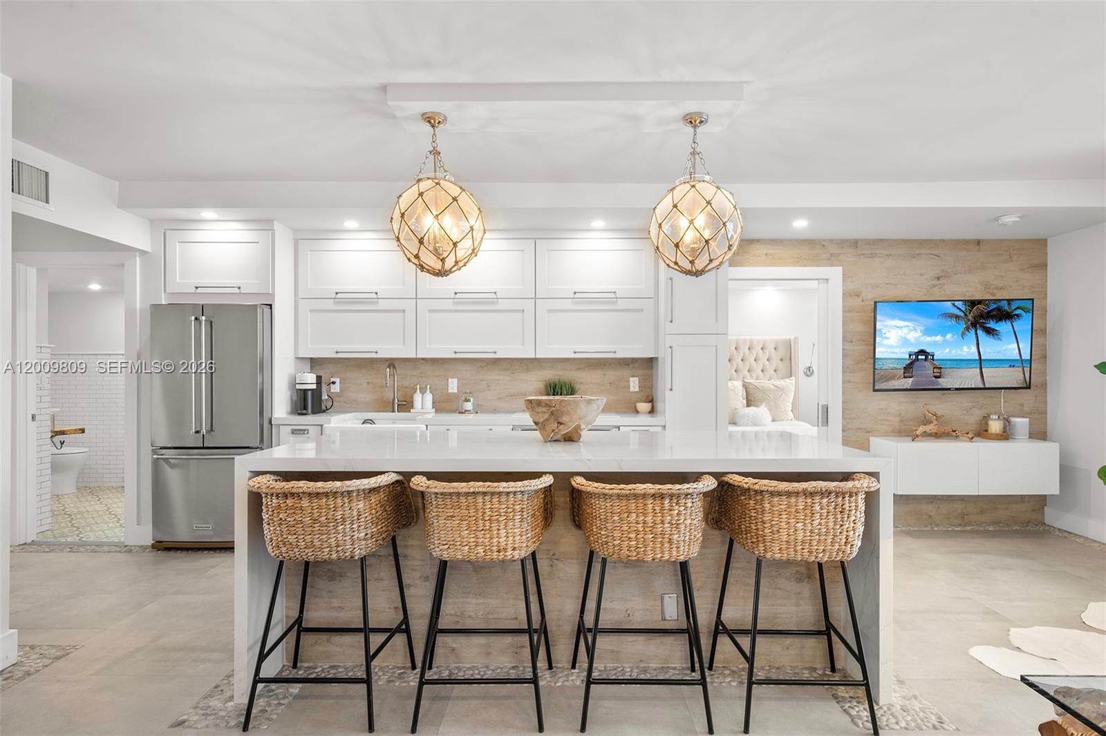 A modern kitchen features white cabinetry, a marble-topped island with four wicker stools, and pendant lighting — 2301 Collins Ave # 1533, Miami Beach FL 33139, MIAMI BEACH, FL