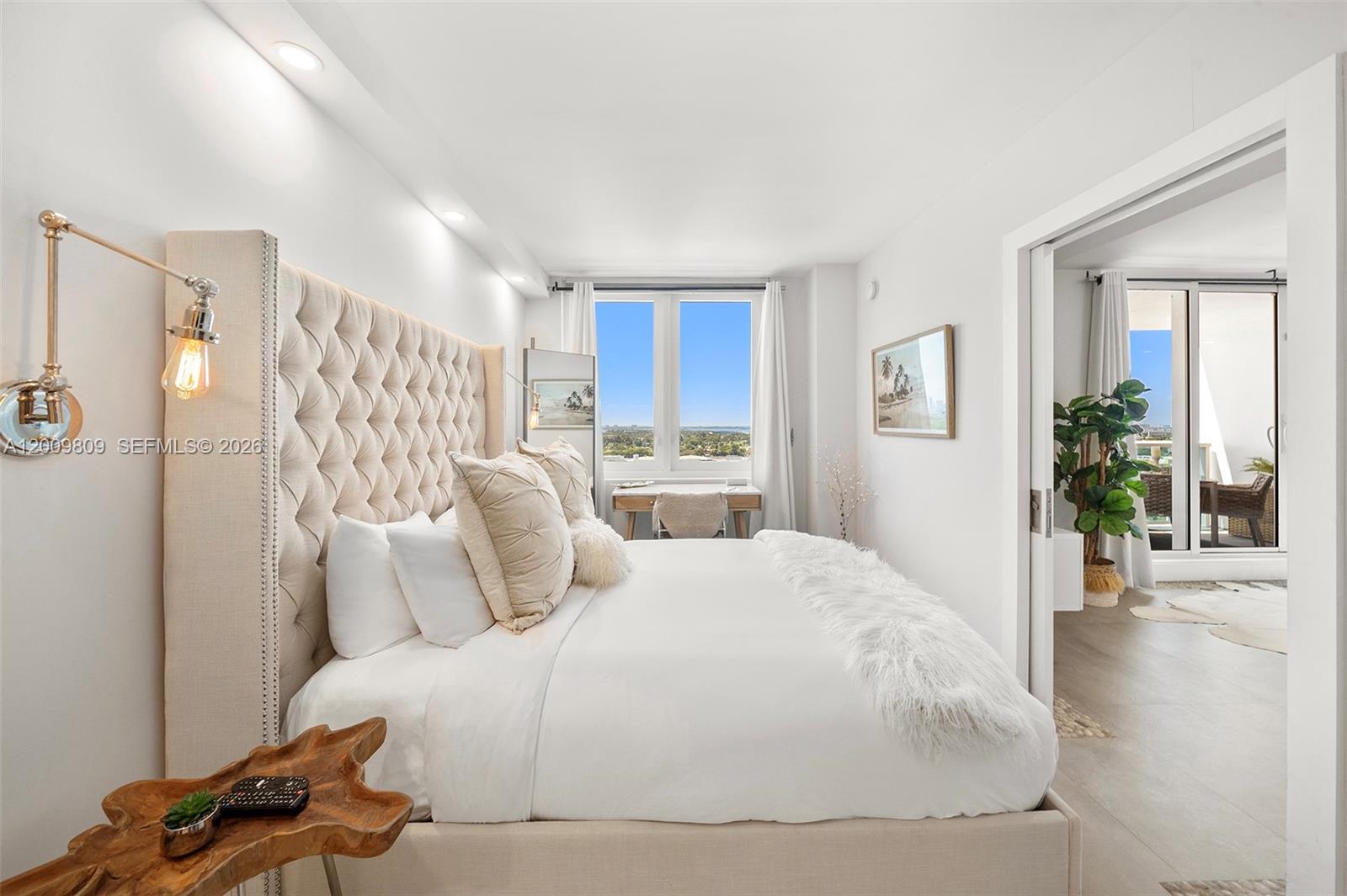A bright bedroom features a tufted headboard, a wooden side table, and a balcony view — 2301 Collins Ave # 1533, Miami Beach FL 33139, MIAMI BEACH, FL