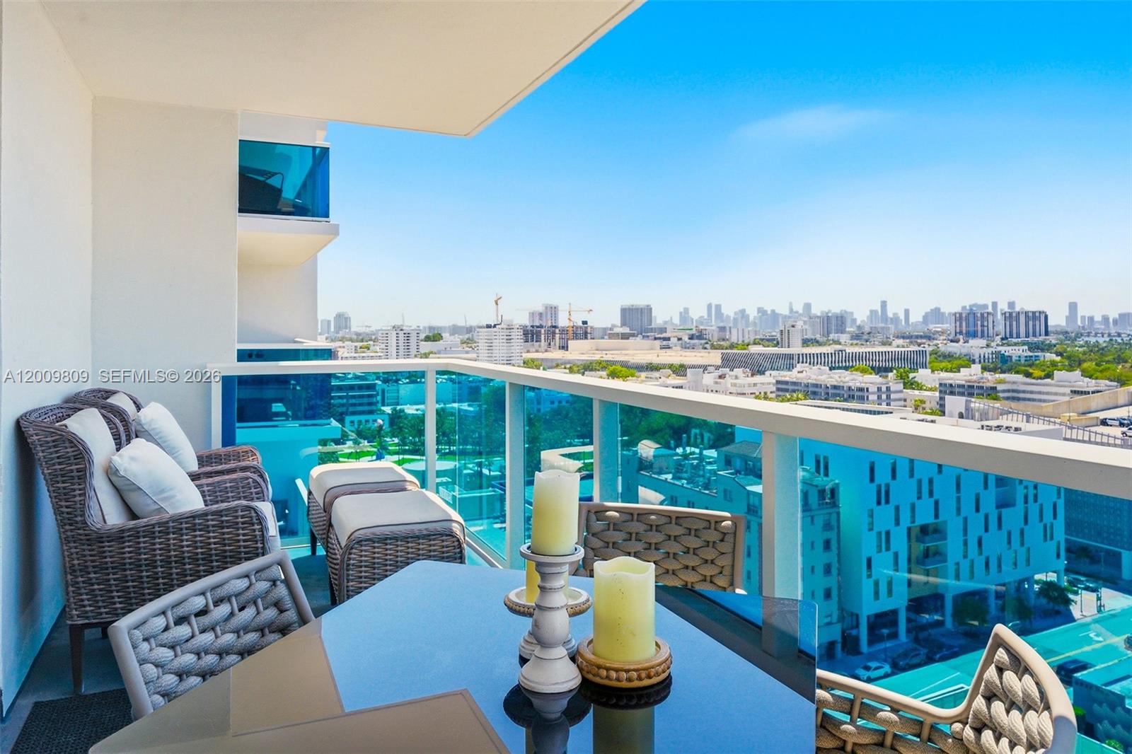 A balcony with outdoor furniture and a glass railing overlooks a city skyline — 2301 Collins Ave # 1533, Miami Beach FL 33139, MIAMI BEACH, FL