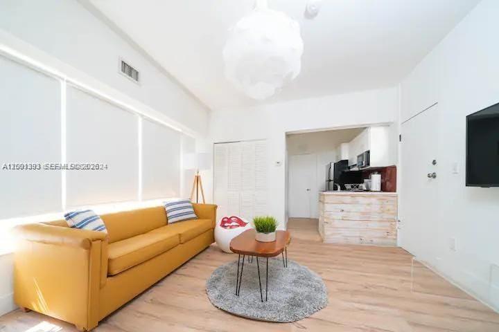 A living room features a yellow sofa, a wooden coffee table, and an open kitchen — 227 1st St # 7, Miami Beach FL 33139, MIAMI BEACH, FL