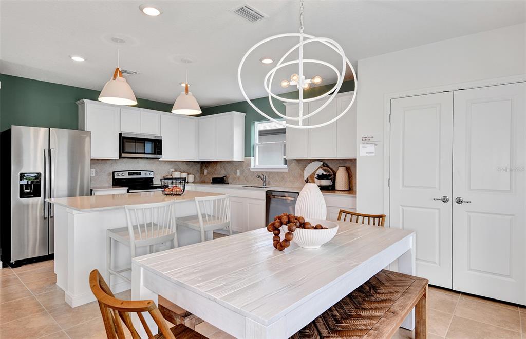 A kitchen with white cabinets, a central island, and a dining area with a wooden table — 10414 HIDDEN BANKS GLEN, PARRISH, FL