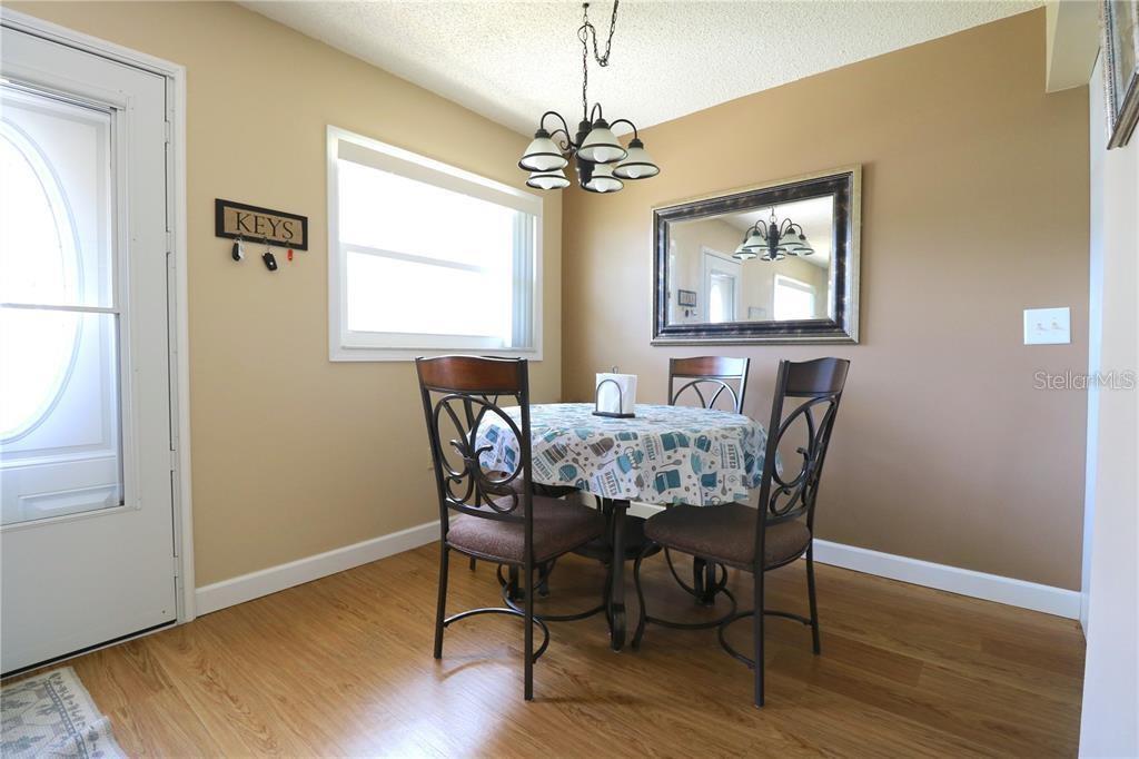 A dining area features a round table with four chairs, a chandelier, and a wall mirror — 11725 BOYNTON LANE UNIT 71A, NEW PORT RICHEY, FL