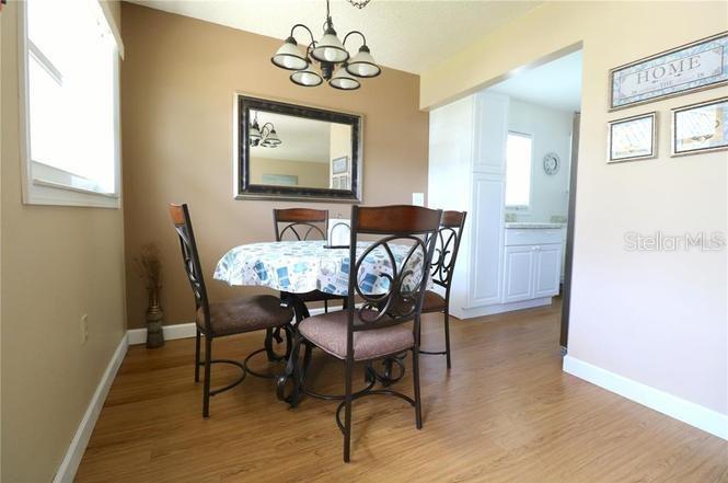 A dining area features a round table with four chairs, a chandelier, and wood flooring — 11725 BOYNTON LANE UNIT 71A, NEW PORT RICHEY, FL