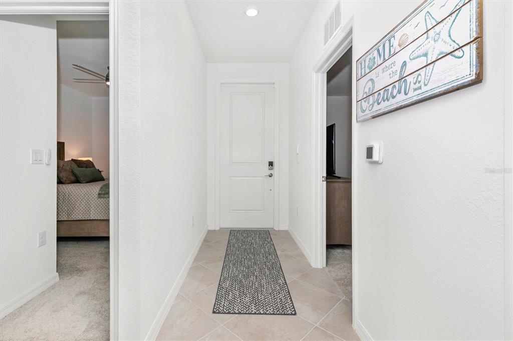 A white hallway features tile flooring, a runner rug, and doorways leading to two bedrooms — 12280 WELLEN GOLF STREET UNIT 203, VENICE, FL