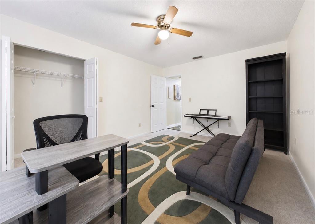 A room with a desk, a futon, a bookshelf, and a patterned area rug — 2450 PELICAN COURT UNIT 202Q, CLEARWATER, FL