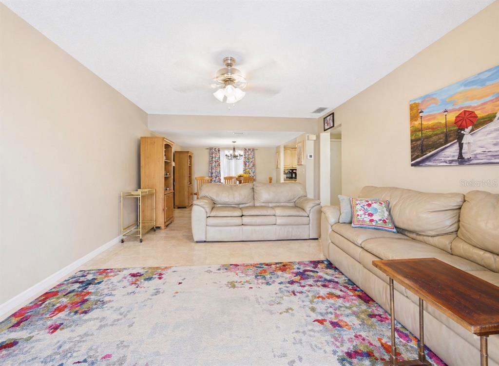 A living room features light-colored tile floors, a colorful area rug, and two leather sofas — 2450 PELICAN COURT UNIT 202Q, CLEARWATER, FL