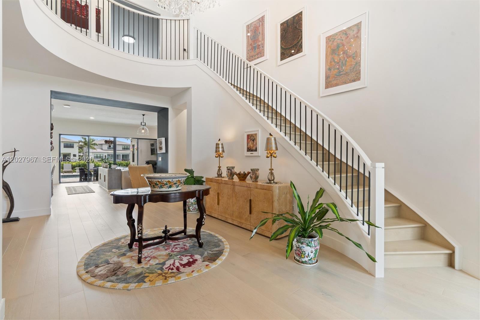A grand foyer features a curved staircase, light wood flooring, and a decorative console table — 20108 Castle Stuart Ave, Boca Raton FL 33434, BOCA RATON, FL