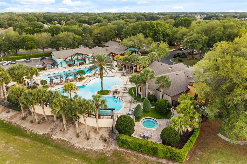 An aerial view shows a community swimming pool complex with a hot tub and clubhouse — 26921 WHITE PLAINS WAY, LEESBURG, FL