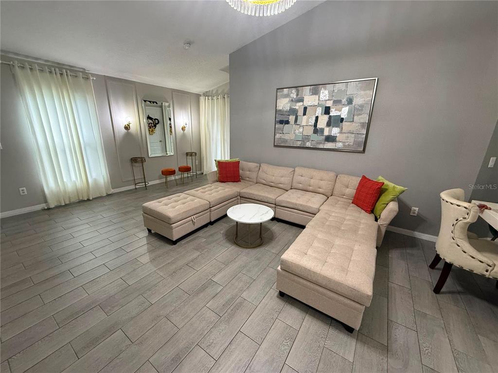 A living room features a large beige sectional sofa, gray tile flooring, and wall art — 1875 ROYAL RIDGE DRIVE, DAVENPORT, FL