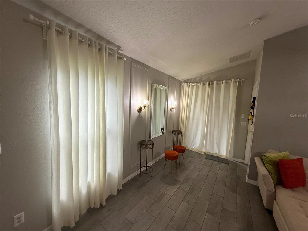 A living room features gray walls with molding, light curtains, and wood-look tile flooring — 1875 ROYAL RIDGE DRIVE, DAVENPORT, FL