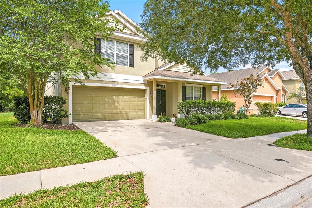 A two-story suburban house with a tan stucco exterior, a garage, and a front lawn — 12230 COLONY LAKES BOULEVARD, NEW PORT RICHEY, FL