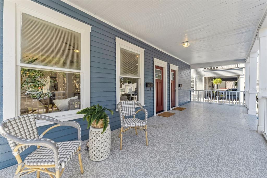 A covered porch with patterned tile flooring, two chairs, a side table, and two red doors — 307 S NEWPORT #1-2 AVENUE, TAMPA, FL