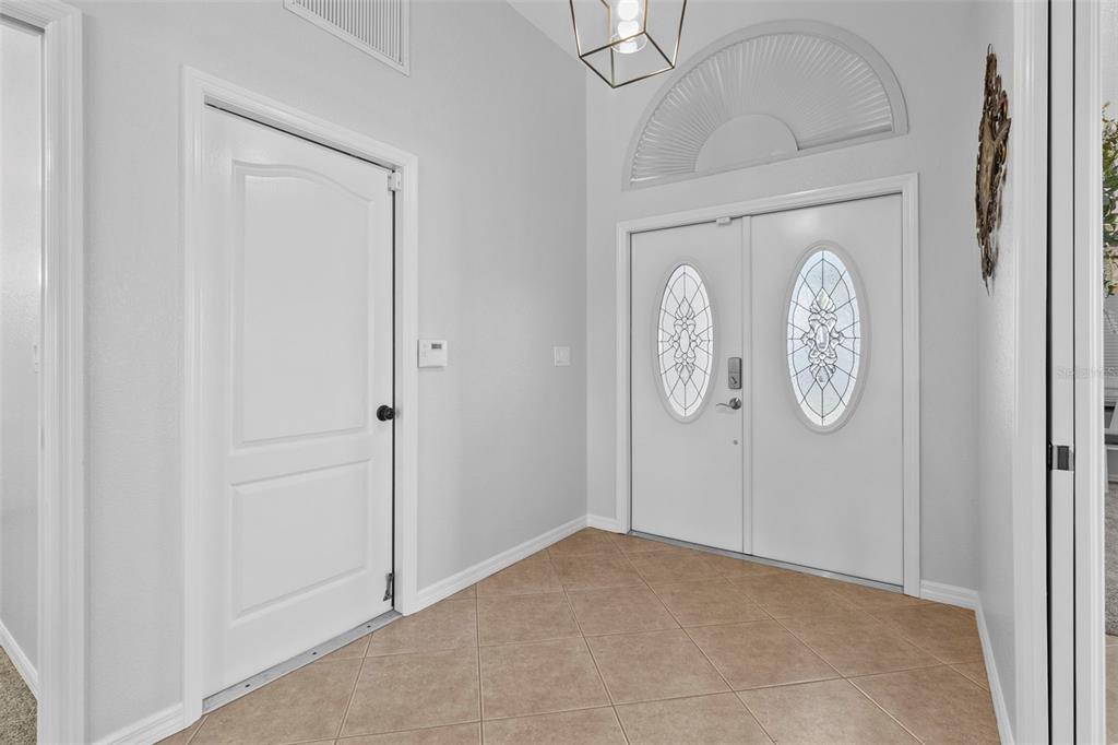 An entryway features light-colored walls, tile flooring, a double front door, and a light fixture — 12962 SW DOUG DRIVE, LAKE SUZY, FL