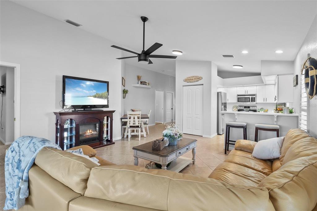 A living room with a tan sectional sofa, a fireplace, and an open kitchen — 12962 SW DOUG DRIVE, LAKE SUZY, FL