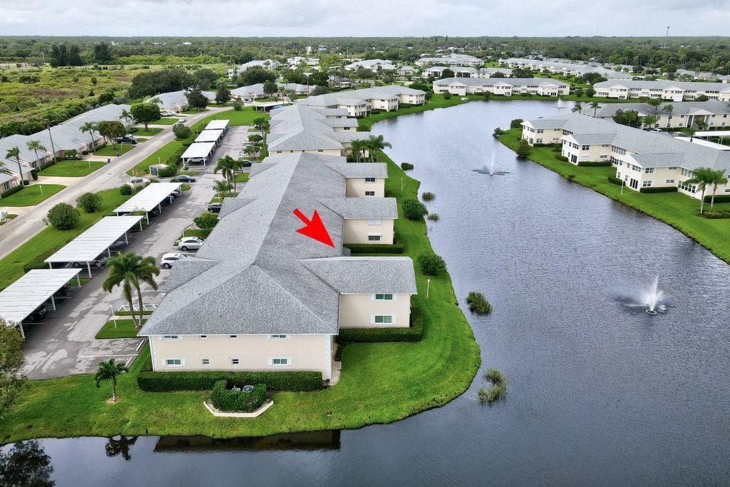 An aerial view of a multi-story residential building with a red arrow pointing to roof — VERO BEACH, FL