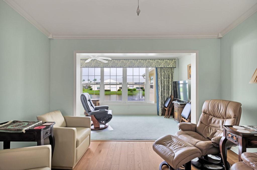 A living room with light green walls, wood flooring, and a view of a pond — VERO BEACH, FL