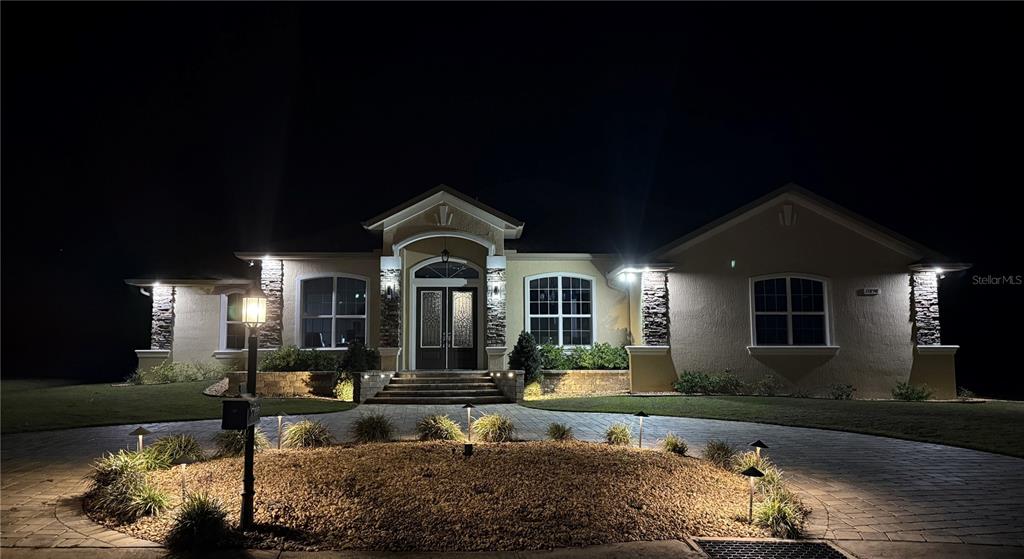 A single-story house with stone accents and illuminated landscaping at night — 17898 SW 72ND STREET ROAD, DUNNELLON, FL
