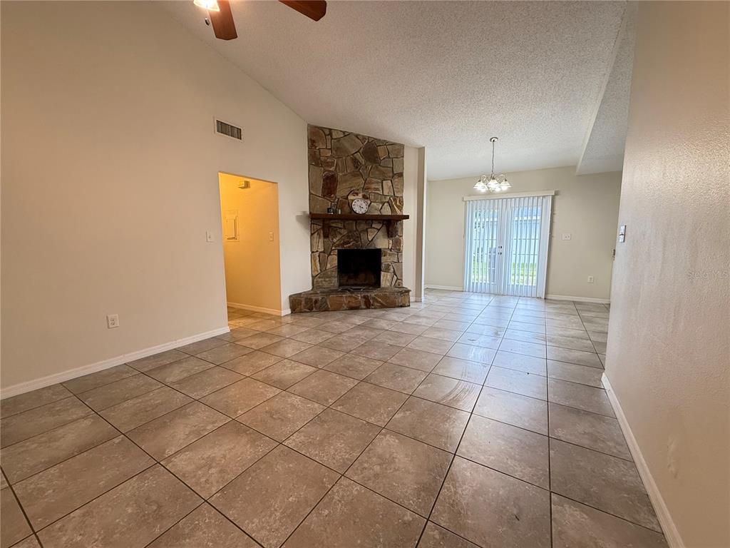 An open living area features large floor tiles, a stone corner fireplace, and sliding glass doors — 3136 JULIA COURT, LAKELAND, FL